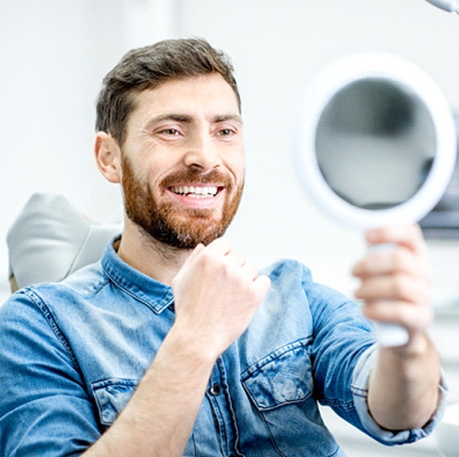 A man wearing a denim shirt admires his fully restored smile in Bartram Park