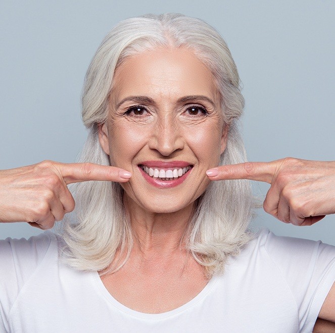 Woman pointing to smile repaired with metal-free restorations