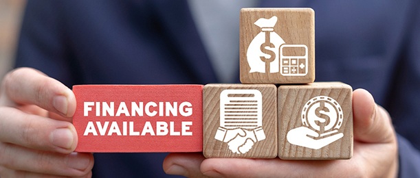 a person holding blocks with different finance-related graphics on them and a big block that says financing available