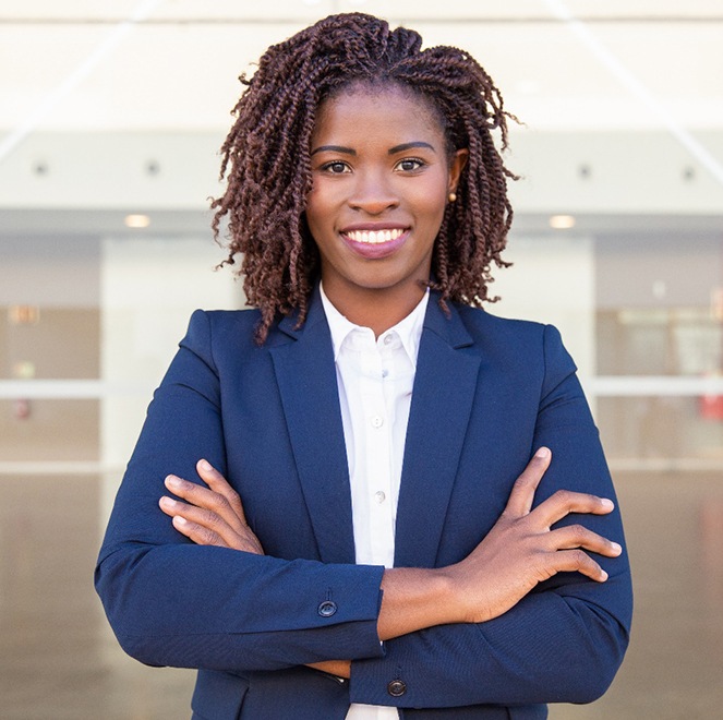 Smiling businesswoman outside near glass wall with her arms folded