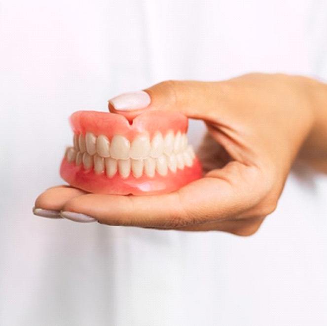 dentist holding a set of full dentures