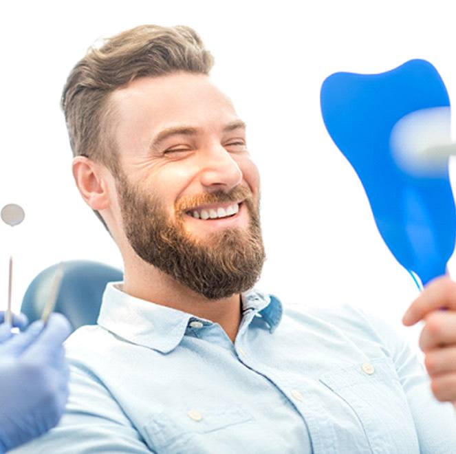 patient with dentures admiring his smile in a mirror