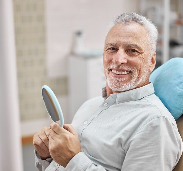 smiling man sitting in dental chair with dentures in Jacksonville 