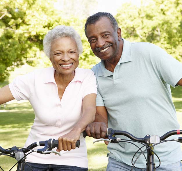 Older couple riding bicycles and smiling outside
