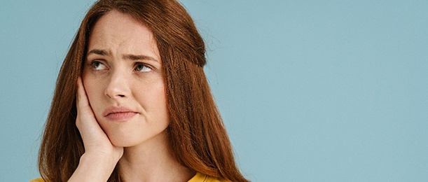 A young woman with tooth pain looking off to the side