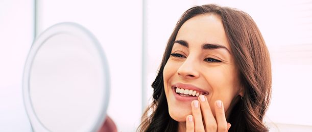 A smiling woman admiring her new dental implants