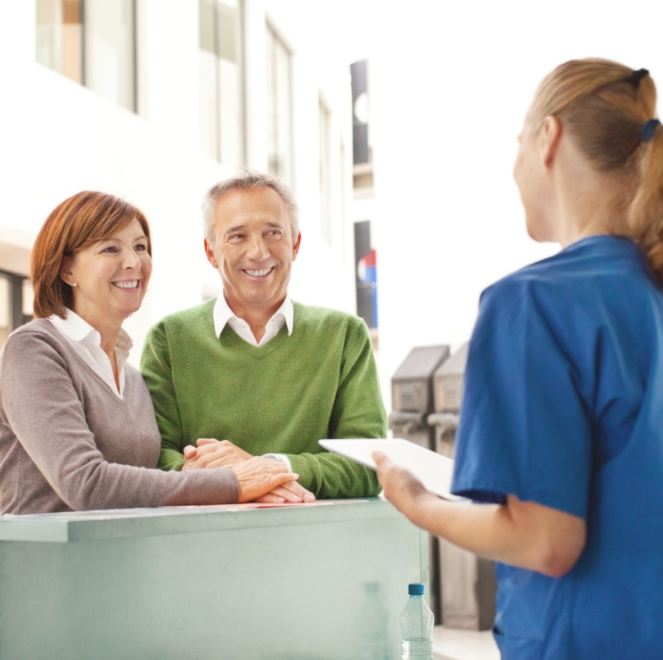 Man and woman discussing dental implant treatment plan with dental team member