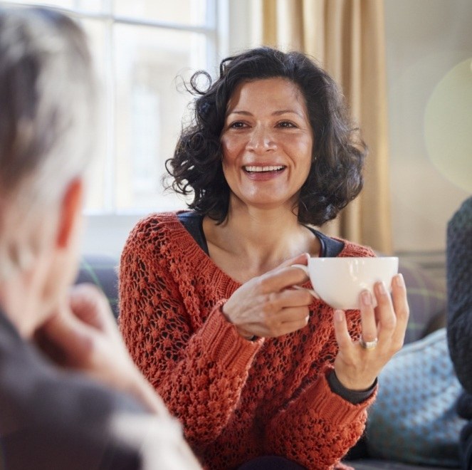 Woman holding cup of coffee after implant supported tooth replacement