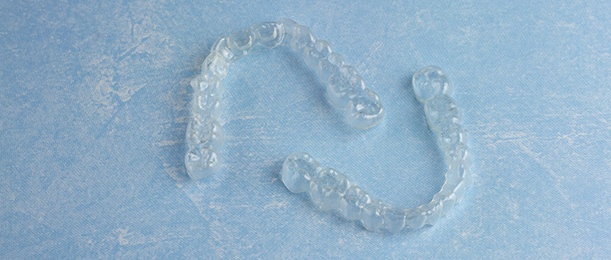 Two Invisalign aligners on blue background