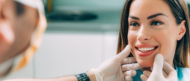 Dentist examining woman’s smile after Invisalign treatment