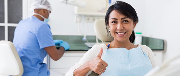 Patient giving thumbs up while sitting in treatment chair
