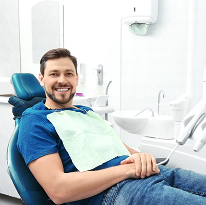 Man in blue shirt smiling in dental chair