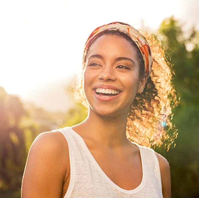 Woman smiling while wearing a white tank top outside