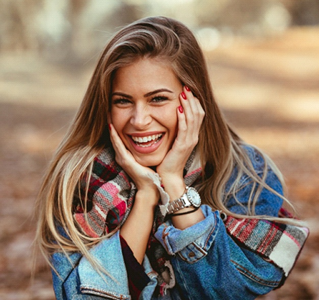 Alt Image Tag: Woman smiling with straight, white teeth outside
