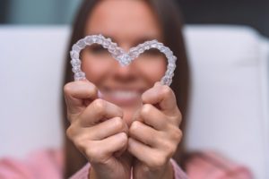 a woman forming a heart with her aligners