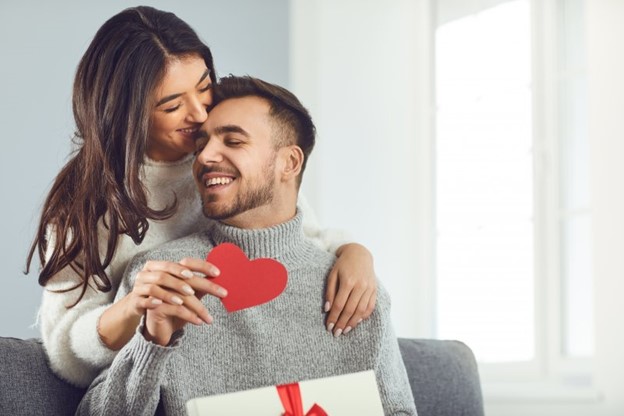 a couple smiling and embracing while holding paper heart