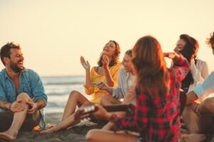 Friends laughing gathered at the beach.