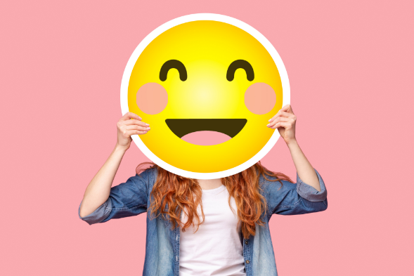 Woman holding emoji smile over face