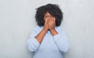 a woman holding her hands over her mouth to hide it