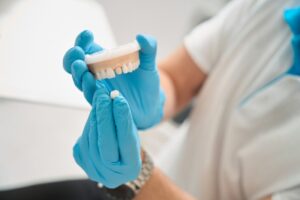 Dentist holding dental crown and model of teeth. 
