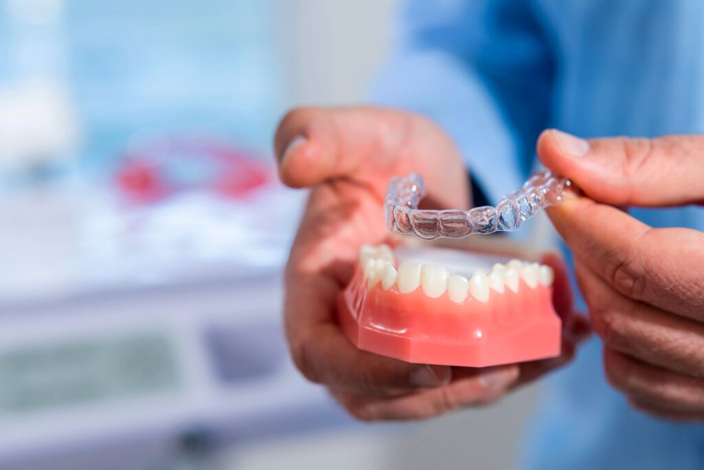 Dentist's hands placing clear aligner over model arch of teeth