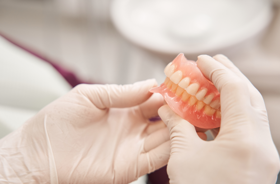 Gloved hands holding dentures
