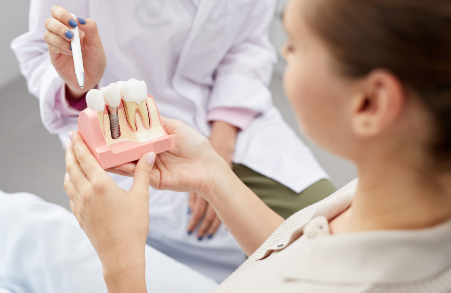 Dentist showing patient model dental implant