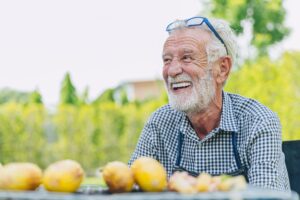Man with white hair sitting outside at a table covered in lemons